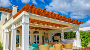 Outdoor vinyl pergola attached to a home with tongue and groove stained white and orange.